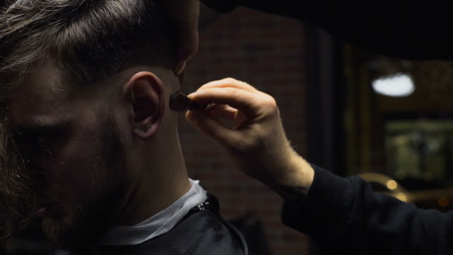 Barber shaves customers nape with straight razor slow motion close up