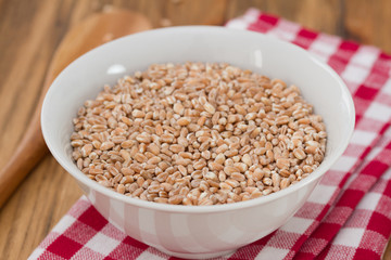 spelt in white bowl with wooden spoon