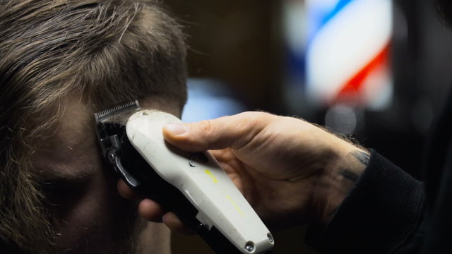 Barber cuts the hair of the client with clipper slow motion close up