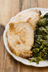 pork with cabbage on white plate on brown wooden background