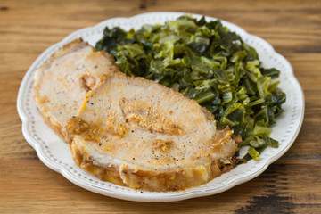 pork with cabbage on white plate on brown wooden background