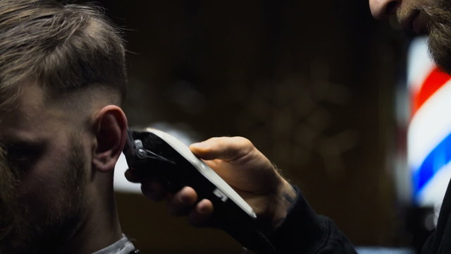 Barber cuts the hair of the client with clipper slow motion close up