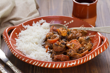 typical portuguese dish feijoada with rice in ceramic bowl and red wine