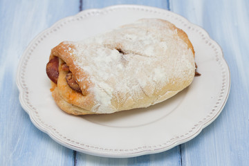 bread with smoked sausage  on white plate on blue wooden background