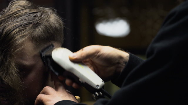 Barber cuts the hair of the client with clipper slow motion close up