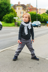 Outdoor portrait of a cute fashion boy in the street, wearing, grey clothes and dark blue shoes