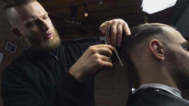 Barber cuts the wet hair of the client with scissors slow motion