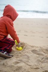 Kid playing on the beach with sand shovel