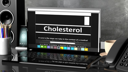 Laptop with Cholesterol information on screen, on desktop with office objects.