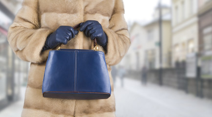 Woman in mink fur coat holding leather bag in hands