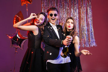 Cheerful man and two women having fun on party