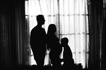 silhouette of a pregnant woman with her husband and child