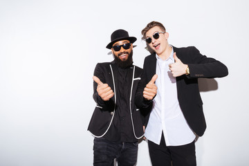 Two happy men standing and showing thumbs up