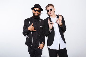 Two cheerful attractive young men standing and showing ok gesture