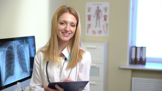 Young attractive female doctor working with medical notes and smiling at the camera. 4k.
