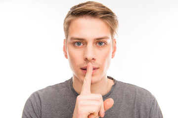 Attrative young man gesturing to make silence