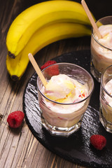 Refreshing milk cocktail with ice cream scoops, raspberry and banana. Toned image. Selective focus