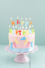 Fondant covered pastels coloured birthday cake with happy birthday candles