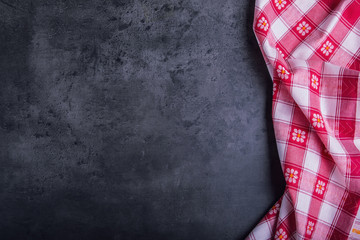 Top view of checkered kitchen tablecloth on granite -  concrete - stone background. Free space for your text or products.