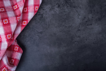 Fototapeta premium Top view of checkered kitchen tablecloth on granite - concrete - stone background. Free space for your text or products.