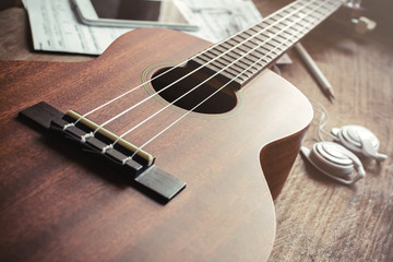 Fototapeta na wymiar Ukulele guitar with earphone on wooden table