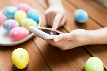 close up of hands with easter eggs and smartphone