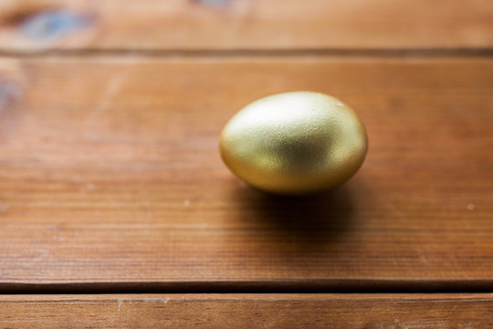 close up of golden easter egg on wood