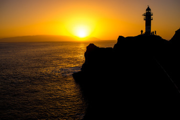 Rocky coastline with lighthouse on the sunset