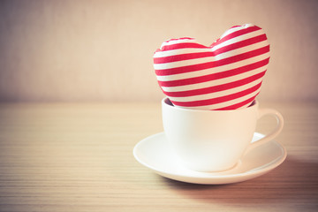Heart in a cup on wooden table - vintage effect style picture
