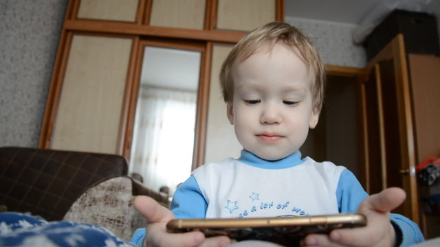 little boy at home watching a video on a mobile phone