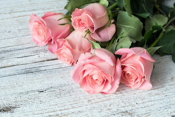 Vintage background / postcard / greeting card. Pink roses on white textured wooden background. Close up