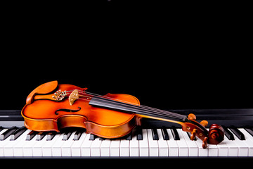 Obraz premium Violin on the piano on a black background