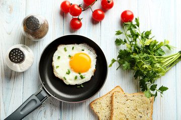 Fried eggs in pan on blue wooden table
