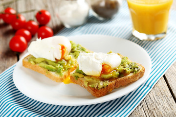 Fototapeta na wymiar Poached eggs with avocado on toasts on grey wooden table