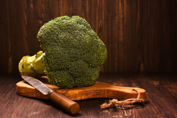 Fresh whole raw broccoli cabbage with vintage knife over grunge wooden background. Toned image. Selective focus