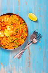 Traditional spanish paella dish with seafood, peas, rice and chicken over grunge blue background. Top view. Selective focus