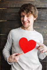 Young cheerful smiling man holding red heart sign