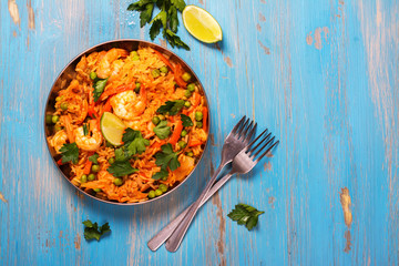 Traditional spanish paella dish with seafood, peas, rice and chicken over grunge blue background. Top view. Selective focus