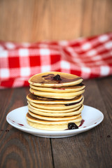 stack of pancakes white plate with cherry jam, red  napkin, brow