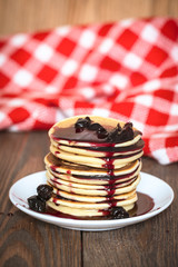 stack of pancakes white plate with cherry jam, red  napkin, brow