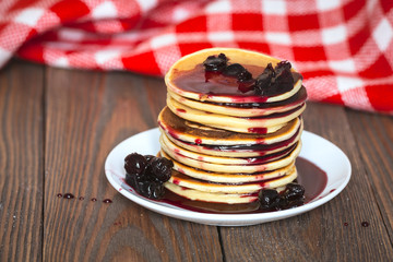 stack of pancakes white plate with cherry jam, red  napkin, brow
