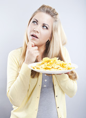 Young girl with potato chips. She thinks. Blonde watch your diet
