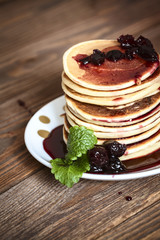 stack of pancakes  white plate  cherry jam, mint leaves, red nap