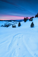 ski track on snow in mountains at sunrise