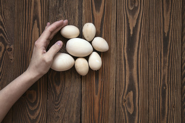 Wood toy eggs, hands, brown wood background