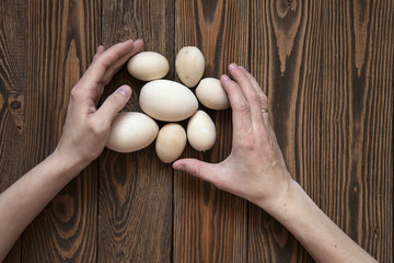 Wood toy eggs, hands, brown wood background