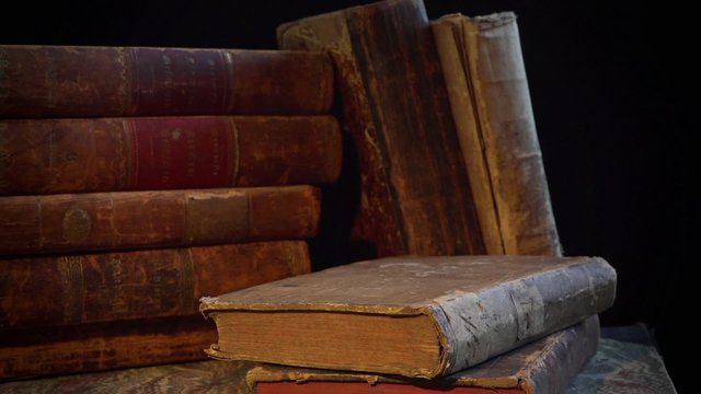Old, aged and weathered books in a stack. Camera movement round them.