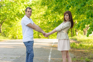 Fototapeta premium young couple holding hands in park on bright sunny day 