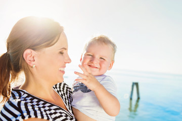 Little boy in mothers arms, sunny day by the water