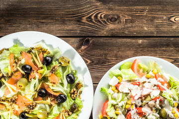 Salads with salmon, olives and vegetables on wooden background with copyspace